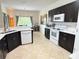Modern kitchen with dark cabinets, white appliances, peninsula island, and ample counter space at 650 Portofino Drive, Poinciana, FL 34759