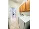 Well-lit laundry room with wooden cabinets and updated washer and dryer, and tiled floors at 650 Portofino Drive, Poinciana, FL 34759