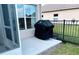 Outdoor patio area with a black grill, next to the screened in lanai, and black metal fence at 650 Portofino Drive, Poinciana, FL 34759