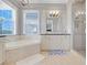 Bright bathroom with a soaking tub, a double vanity, and a glass-enclosed shower at 1021 Castle Pines Ct, Reunion, FL 34747