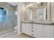 Bathroom with double sink vanity, granite counters, and a tiled walk-in shower with glass doors at 1021 Castle Pines Ct, Reunion, FL 34747