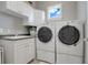 Bright laundry room featuring white cabinetry, granite counters, stainless steel sink, and front loading washer and dryer units at 1021 Castle Pines Ct, Reunion, FL 34747