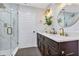 Bright bathroom features a glass-enclosed shower, double sinks, dark wood cabinets, and modern lighting at 1176 Epson Oaks Way, Orlando, FL 32837