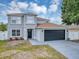 Elegant two-story home with a gray exterior, a black garage door, and charming front yard landscaping at 1176 Epson Oaks Way, Orlando, FL 32837