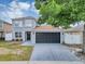 Inviting two-story home featuring a gray exterior, a black garage door, and well-manicured landscaping at 1176 Epson Oaks Way, Orlando, FL 32837