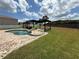 Large backyard with green lawn, in-ground pool, slide, and pergola with an outdoor seating area at 1505 Chevington Ct, Orlando, FL 32824
