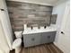 Bathroom featuring a gray wood accent wall, double sink vanity with quartz countertop and gray cabinets at 1505 Chevington Ct, Orlando, FL 32824