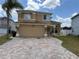 Two-story home with tan exterior and brick paver driveway under a blue sky with light, puffy clouds at 1505 Chevington Ct, Orlando, FL 32824