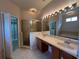 Primary bathroom boasts dual sinks, large mirror, walk-in shower, and access to walk-in closet at 15408 Groose Point Ln, Clermont, FL 34714