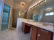 Well-lit bathroom featuring a walk-in shower, dual sink vanity, and walk-in closet access at 15408 Groose Point Ln, Clermont, FL 34714