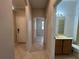 Neutral hallway with tile flooring leading to rooms, including a bathroom with vanity sink at 15408 Groose Point Ln, Clermont, FL 34714