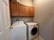 Bright laundry room featuring a modern washer, dryer, and overhead cabinets for storage at 15408 Groose Point Ln, Clermont, FL 34714
