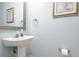 A bathroom features a pedestal sink, a decorative mirror, and soft blue walls at 156 Bristol Forest Trl, Sanford, FL 32771