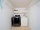 Bright laundry room features a washer, dryer, and overhead shelving for convenient storage at 1814 Leroy Dr, Haines City, FL 33844