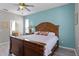 Bedroom featuring blue walls, wood-look floors, a ceiling fan, and a large bed with a decorative headboard at 209 Rosso Dr, Davenport, FL 33837