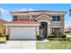 Exterior view of a two-story home with red tile roof, a two-car garage, and manicured landscaping at 209 Rosso Dr, Davenport, FL 33837
