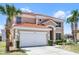 Two-story home with a red tile roof, two-car garage, and manicured landscaping in front of palm trees at 209 Rosso Dr, Davenport, FL 33837