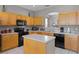 Kitchen featuring wood cabinets, black appliances, an island, and a tile floor at 209 Rosso Dr, Davenport, FL 33837
