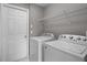 Laundry room with a front-loading washer and dryer, a wire shelf, and white trim at 209 Rosso Dr, Davenport, FL 33837
