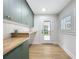 Stylish laundry room with ample storage in green cabinets, butcher block countertops and backyard access at 217 W Bay St, Winter Garden, FL 34787