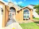 Charming home exterior featuring an arched window, a decorative front door, and well-kept landscaping at 2346 Lily Pad Ln, Kissimmee, FL 34743