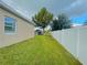 Side yard featuring a well-maintained lawn, a white fence, and mature trees creating a serene outdoor space at 247 Whispering Pines Way, Davenport, FL 33837