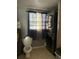 Small utility bathroom with standard toilet, stacked washer and dryer and blue curtains at 311 Congress Ave, Auburndale, FL 33823