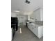 Updated kitchen showcasing white cabinets, contrasting black hardware and appliances, and gray laminate flooring at 4385 Ne 2Nd Ct, Ocala, FL 34479