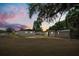 An ample backyard features multiple outbuildings at twilight, with a grassy lawn and mature tree coverage at 620 Plum Ln, Altamonte Springs, FL 32701