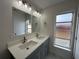 Bathroom vanity with double sinks and gray cabinets, and a window at 705 Wood Ln, Kissimmee, FL 34759