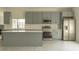 Modern kitchen featuring gray cabinets, stainless steel appliances, a center island and tile backsplash at 705 Wood Ln, Kissimmee, FL 34759