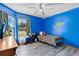 A colorful bedroom with wood-look floors, a ceiling fan, blue walls, and large windows for plenty of natural light at 710 California Ave, St Cloud, FL 34769