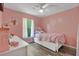 Cozy pink bedroom featuring a white bed frame, a ceiling fan and a bright window at 710 California Ave, St Cloud, FL 34769