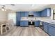 An eat-in kitchen featuring matching blue cabinets, stainless steel appliances, and a ceiling fan with a light at 710 California Ave, St Cloud, FL 34769