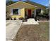 Charming yellow single-story home featuring a red front door, white shutters, and well-maintained landscaping at 716 Grove Ave, Orlando, FL 32805