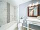 Bathroom with combined tub and shower, tiled walls, marble vanity, and decorative mirror at 7823 Bell Blvd, Orlando, FL 32810