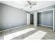 Well-lit bedroom with neutral gray walls, wood-look tile floors, ceiling fan, and closet at 7823 Bell Blvd, Orlando, FL 32810