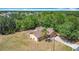Aerial view of a tan single-story home surrounded by trees and a chain link fence and a long driveway at 923 Gascony Ct, Kissimmee, FL 34759