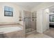 Bright bathroom showcasing a large soaking tub, a glass-enclosed shower, and neutral tile at 11120 Whistling Pine Way, Orlando, FL 32832