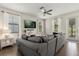 Bright living room features wood floors, comfortable gray sofa, and plenty of natural light at 11120 Whistling Pine Way, Orlando, FL 32832