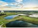 Aerial view of a golf course with multiple ponds surrounded by lush greenery under a cloudy sky at 1231 Sandwedge St, Davenport, FL 33896