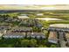 Aerial view of townhomes with a golf course and multiple ponds in the distance at sunset at 1231 Sandwedge St, Davenport, FL 33896