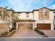 Townhome exterior showcasing brick and stucco facade, complemented by a paver driveway and well-maintained landscaping at 1231 Sandwedge St, Davenport, FL 33896