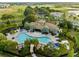 Aerial view of a community pool and clubhouse surrounded by palm trees, landscaping, and a nearby golf course at 1231 Sandwedge St, Davenport, FL 33896