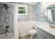 Bathroom with floral wallpaper, white wainscoting, marble-look shower, and gray vanity at 1400 Florida Ave, St Cloud, FL 34769