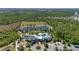 Aerial view of a community amenity center with a pool, pond, playground, clubhouse, parking and surrounding wooded areas at 17324 Bracken Fern Ln, Clermont, FL 34714