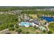 Beautiful aerial view of a modern community clubhouse featuring a pool, splashpad, green space, parking, and playground at 17324 Bracken Fern Ln, Clermont, FL 34714