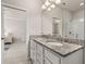 Bathroom featuring double vanity with granite countertop, large mirror, and glass enclosed shower at 17324 Bracken Fern Ln, Clermont, FL 34714