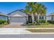 Charming single-story home with a brick driveway, two-car garage, and tropical palm trees at 17324 Bracken Fern Ln, Clermont, FL 34714