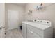 Functional laundry room with a washer, dryer, overhead shelving and tile flooring at 17324 Bracken Fern Ln, Clermont, FL 34714